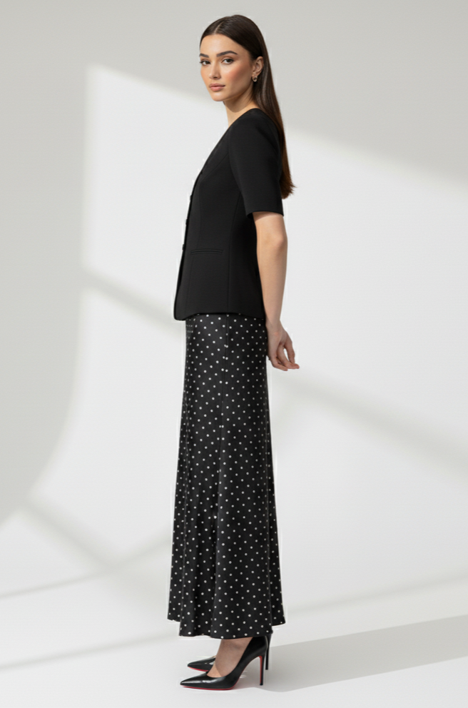 Woman wearing a black top and polka dot pants on a white background